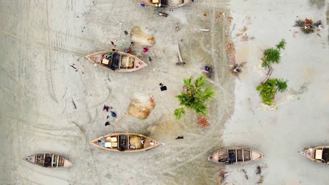 Vista-Aérea-De-Pescadores-Reparando-Redes-De-Pesca-Además-De-Barcos-Tradicionales-De-Madera-En-La-Playa-De-Kuakata,-Bangladesh
