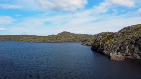 Rocky-cliffs-along-open-lake-of-Embalse-de-las-Tejoneras,-spain