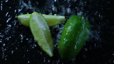 Cinematic-footage-of-sliced-limes-being-washed-on-a-dark-working-surface-in-slow-motion,-Slomo