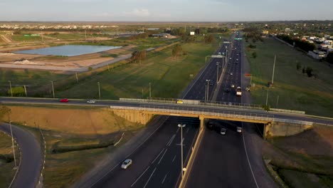 An-aerial-shot-of-vehicles-moving-along-the-bridge-over-the-road-and-under-the-bridge,-that-is-located-close-to-Peaje-Hudson-Toll,-Buenos-Aires,-Argentina