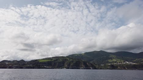 Southern-shores-of-San-Miguel-Island,-Azores,-Portugal,-filmed-from-a-boat-with-the-waves-of-the-ocean-in-the-foreground