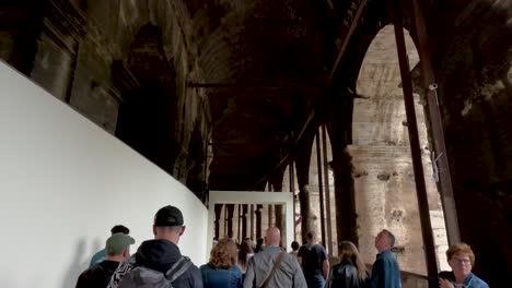 POV-Caminando-Con-Un-Grupo-De-Turistas-Dentro-De-Los-Pasillos-Con-Arcos-En-El-Coliseo-De-Roma