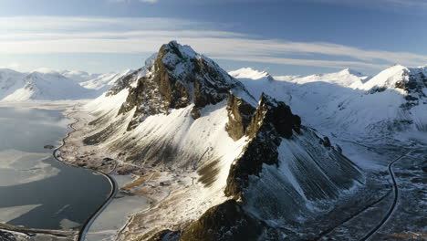 Luftaufnahme-Einer-Felsigen-Bergkette,-Verschneit,-Winterabend-In-Südisland