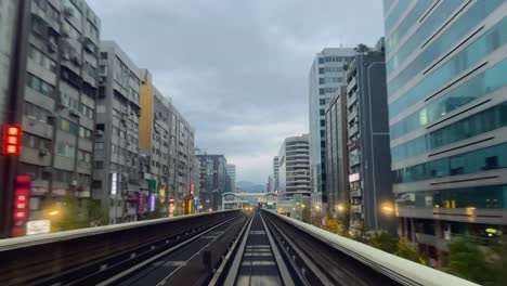 Front-view-of-Taipei-metro-driving-through-scenic-cityscape,-Zhongxiao-Dunhua-metro-station