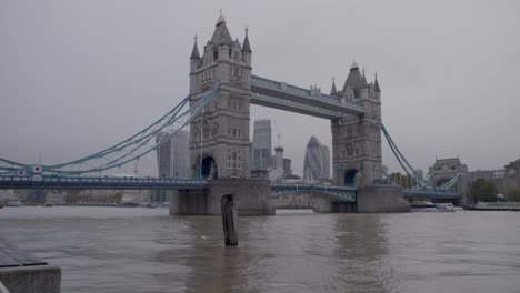 Boat-rides-under-the-famous-Tower-Bridge-in-London-on-a-rainy-day,-static-shot