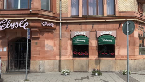 Eingang-Zum-Restaurant-Elyse-In-Malmö:-Skandinavisches-Kulinarisches-Erlebnis-Und-Restaurantszene-Im-Bezaubernden-Stadtbild-Schwedens,-Vorbeigehende-Frau-Und-Vorbeifahrende-Frau