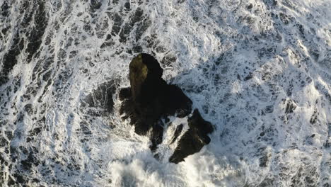 Luftaufnahme-Mit-Neigung-über-Wellen-Und-Einem-Steilen-Reynisdrangar-Felsen-Im-Sonnigen-Island