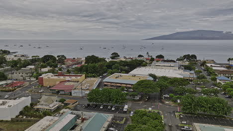 Lahaina-Maui-Hawaii-Aérea-V5-Toma-De-Establecimiento,-Drone-Sobrevolando-El-Centro-De-La-Ciudad-A-Bajo-Nivel-Con-Vista-A-La-Isla-Molokaʻi-Al-Otro-Lado-Del-Mar-Sobre-El-Horizonte---Filmada-Con-Cine-Mavic-3---Diciembre-De-2022