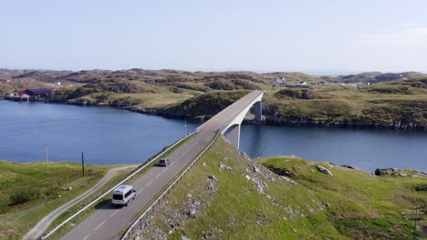 Tracking-drone-shot-of-two-cars-crossing-the-Scalpay-bridge,-near-the-Isle-of-Harris-on-the-Outer-Hebrides-of-Scotland