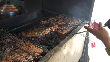 grill-cooking-river-prawns-in-metal-cage-on-hot-charcoal-at-thailand-fish-market