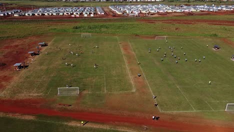 Drone-slow-strafe-past-two-football-games-with-active-play-and-buildings-in-the-background---Posadas-hipodrome