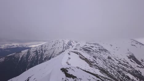 Schneebedeckter-Bergrücken-Mit-Niedrigen-Wolken,-Die-Den-Gipfel-Verbergen