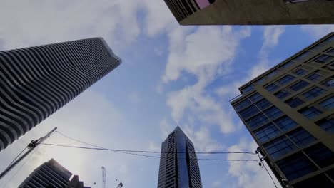 Toronto-Yonge-Und-Wellesley-Downtown-Worms-Blick-Von-Unten-Nach-Oben-Mit-Wolken,-Die-Sich-Im-Zeitraffer-Bewegen,-Mit-Postmodernem-Architektonischem-Wunderwerk,-Das-Der-Skyline-Hinzugefügt-Wurde,-Wobei-Schönheit-Mit-Stil-Den-Weg-Weist