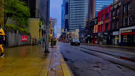 Yonge-Wellesley-Calles-Mojadas-Después-De-La-Lluvia,-Los-Ciclistas-Entregan-Comida-El-Día-De-Verano-En-Un-Espejo-De-Vidrio-Futurista-Posmoderno,-Reflejo-De-Nuevos-Edificios-En-El-Fondo-Y-Edificios-De-Ladrillo-En-El-Frente