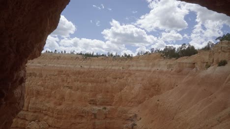 Handaufnahme-Aus-Einer-Kleinen-Felsbucht-Mit-Blick-Auf-Eine-Klippe-Aus-Orangefarbenen-Hoodoo-Sandsteinformationen-In-Der-Wüste-Im-Süden-Utahs-An-Einem-Wolkigen,-Warmen-Sommertag