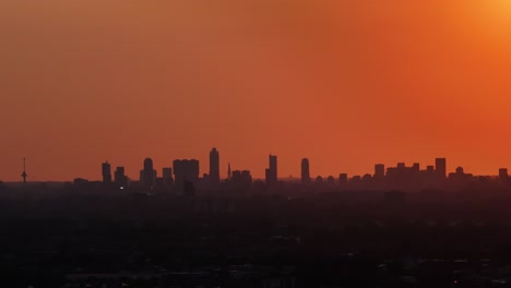 Sun-setting-with-dramatic-orange-skyline-over-Rotterdam,-Netherlands-below