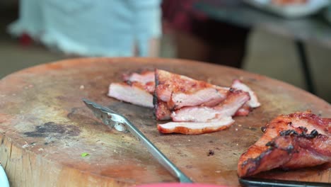 Poner-En-Un-Plástico-Una-Porción-De-Cerdo-Y-Pollo-A-La-Parrilla,-Un-Alimento-Básico-Para-La-Población-Local-Que-Compran-A-Los-Vendedores-Ambulantes-En-El-Mercado-Nocturno-De-Fin-De-Semana-De-Chatuchak,-En-Bangkok,-Tailandia.