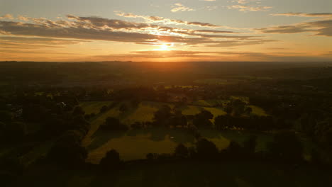 Establishing-Drone-Shot-into-the-Sun-Over-Grass-Fields-at-Golden-Hour-Sunrise