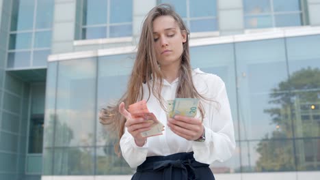 Attractive-business-woman-counting-money-near-office-building,-close-up