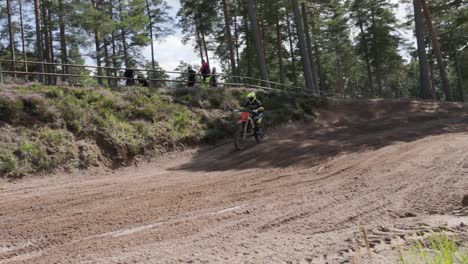 A-motocross-rider-accelerating-at-high-speed-out-of-a-berm-on-a-dirt-bike-at-Gnagardalen,-Sweden
