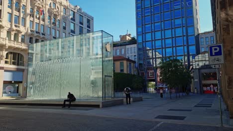 Static-shot-of-locals-and-tourists-walking-around-a-fountain-at-Apple-Liberty-Square-in-Milan,-Italy-on-a-sunny-day