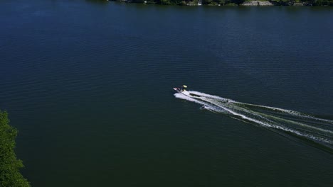 Eine-Drohne-Folgt-Einem-Familien-Schnellboot,-Das-Zwei-Wakeboarder-Auf-Dem-Wasser-Des-Killarney-Lake-In-Turtle-Mountain-Im-Südwesten-Von-Manitoba,-Kanada,-Zieht