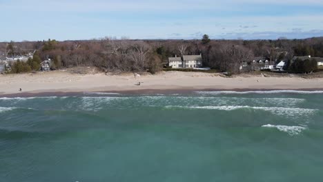 Lake-Michigan-coastline-with-waves-and-small-private-buildings,-aerial-view