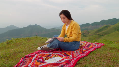 woman-reading-on-a-windy-mountaintop-with-a-bright-red-blanket