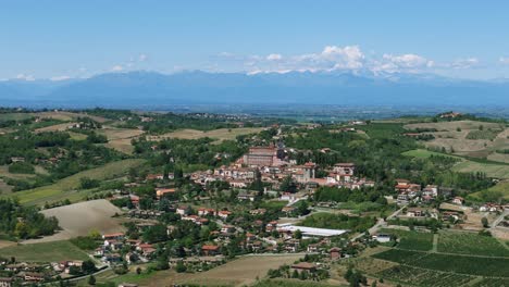 Pequeña-Ciudad-De-Piamonte-En-Italia-Con-La-Cordillera-De-Los-Alpes-Al-Fondo