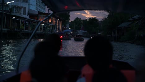 Ein-Hölzernes-Ausflugsboot-Bewegt-Sich-In-Richtung-Des-Flusses,-Wo-Die-Sonne-Untergeht,-Während-Der-Rest-Der-Boote-Zurück-In-Den-Kanal-Des-Schwimmenden-Marktes-Amphawa-In-Thailand-Fährt