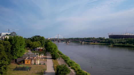 Establishing-view-of-Warsaw-river-and-suspension-bridge-in-distance-off-side-of-park-and-railroad-track-by-stadium