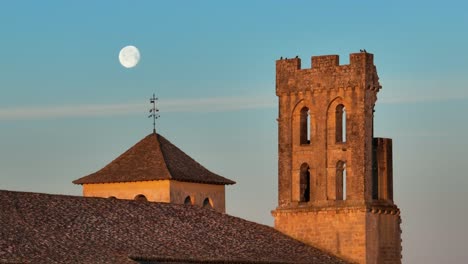Very-close-up-of-the-moon-passing-behind-a-church-steeple,-aerial-view-at-moonset