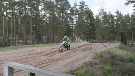 A-slow-motion-shot-of-a-motocross-rider-cautiously-riding-over-a-ramp-with-his-motorbike-on-a-race-track