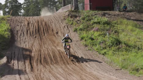A-slow-motion-shot-of-a-motocross-rider-getting-airborne-jumping-off-a-ramp-with-a-motorcycle-on-an-offroad-race-track,-Gnagardalen,-Sweden