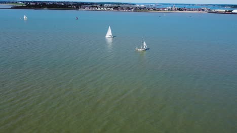A-few-sailboats-near-the-coastline-of-Port-Felixstowe,-UK-filmed-on-a-bright-sunny-day