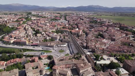 Vista-Aérea-Sobre-El-Acueducto-De-Segovia-Al-Lado-De-La-Plaza-Oriental-Rodeada-Por-El-Paisaje-De-La-Ciudad-En-Un-Día-Claro-Y-Soleado