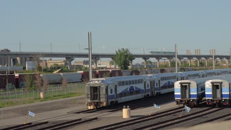 Montreal-Réseau-Express-Métropolitain-REM-Train-Running-on-a-Elevated-Line-Past-Several-Stopped-EXO-Commuter-Trains-During-Golden-Hour