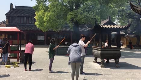 Gente-Rezando-Con-Incienso-Y-Velas-Encendidas-En-El-Templo-Longhua-En-Shanghai,-China-En-Un-Día-Soleado