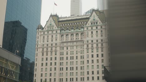 Foreground-reveal-pass-silver-building-reflection-of-plaza-hotel,-new-york-city