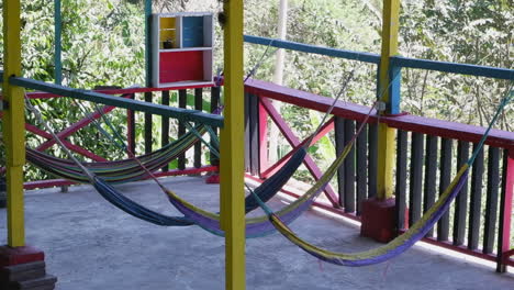 Colorful-hammocks-swing-gently-in-breeze-on-balcony-of-forest-hostel