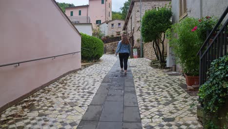 Rear-Of-A-Woman-Visiting-The-Small-Mountain-Village-Of-Rasiglia,-Province-of-Perugia,-Umbria-Italy