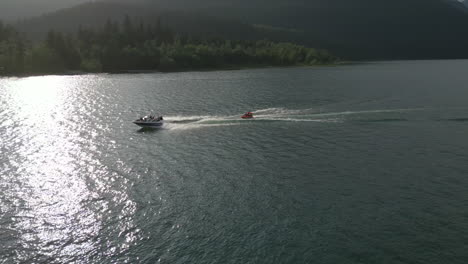 Luftaufnahme-Eines-Schnellboots,-Das-Menschen-In-Einem-Schwimmenden-Gerät-Auf-Dem-British-Columbia-Lake-Zieht