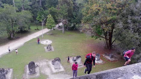 Tourists-climb-a-steep-pyramid-at-Tikal,-Mayan-ruin-site-in-Guatemala