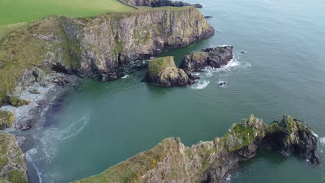 Aerial-shot-of-secluded-beach-behind-a-rugged-headland-on-The-Copper-Coast-Waterford-Ireland