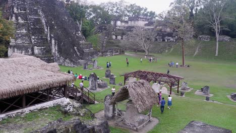 Tourists-roam-Central-Plaza-by-Grand-Temple-of-Tikal,-Mayan-ruins,-GTM