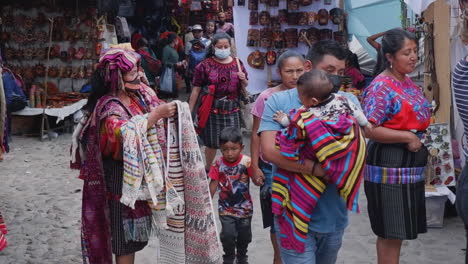 Woman-vendor-at-Guatemala-street-market-sorts-fabrics,-covid-masks