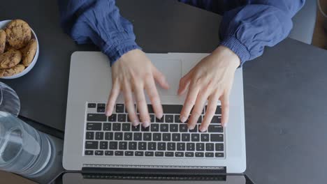 Female-hands-typing-on-a-laptop-keybord,-top-down-view