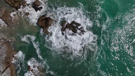 Top-down-shot-overhead-waves-crashing-over-a-large-rock-at-Newwquay