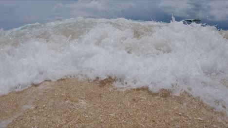 Wave-crashing-on-sandy-beach-low-angle,-slow-motion