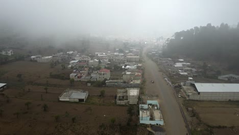 Aerial-enters-sleepy,-foggy-mountain-town-in-rural-Guatemala-valley